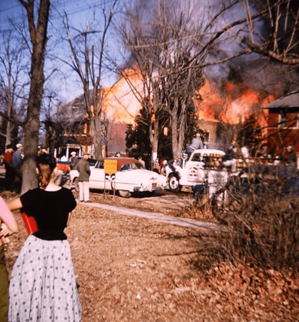 Men and women gather outside the burning brick 2.5-story Katie Jane Nursing Home in Warrenton, February 17, 1957.