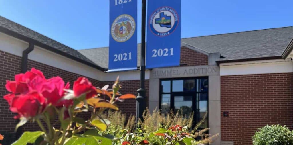 Exterior photo of the WCHS Museum and Library with red flowers in bloom.