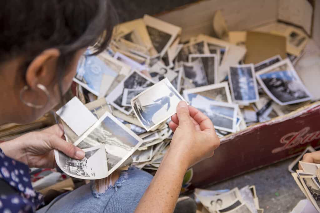 A woman sorts through old photos in a shoebox.