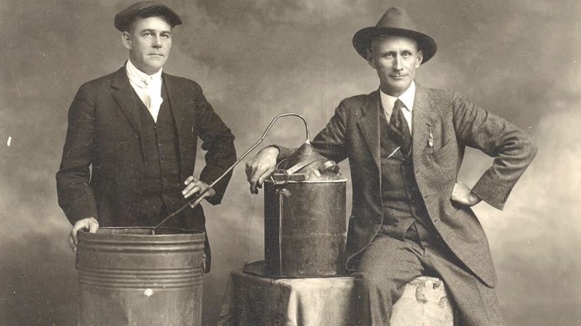 Two men pose with their homemade moonshine still