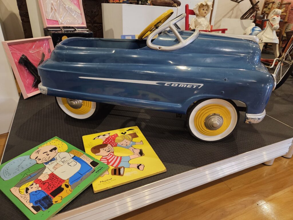 A comet race car and a collection of children's books as part of the toy exhibit.