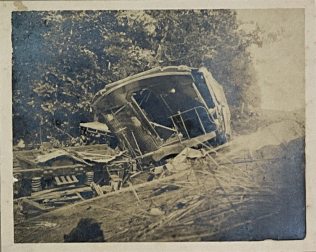 Severely damaged train car at the bottom of an embankment.