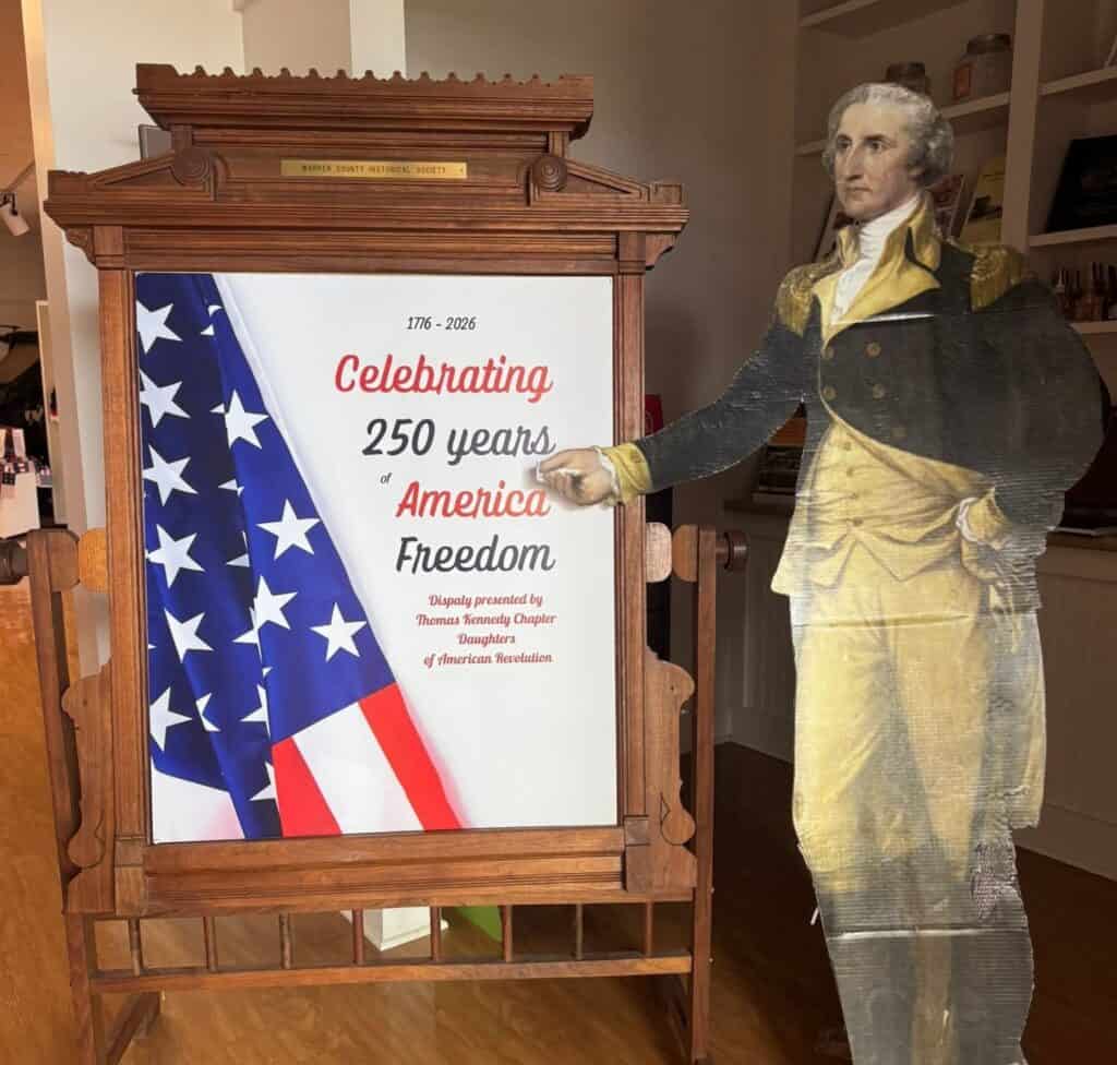 George Washington figure pointing at Warren County 250th anniversary display.