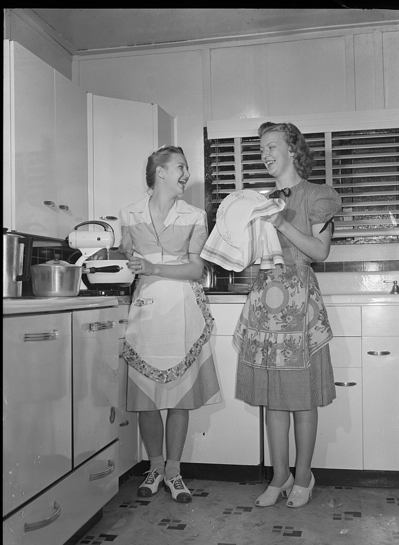 Two daughters of a Rural Electrification Administration cooperative member using an electric appliance in their farm kitchen, Dunklin County, Missouri, 1942.